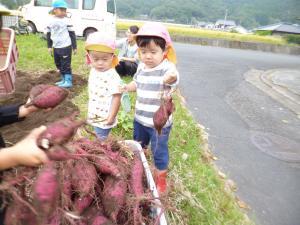 大きな芋をもった小さい子どもたち